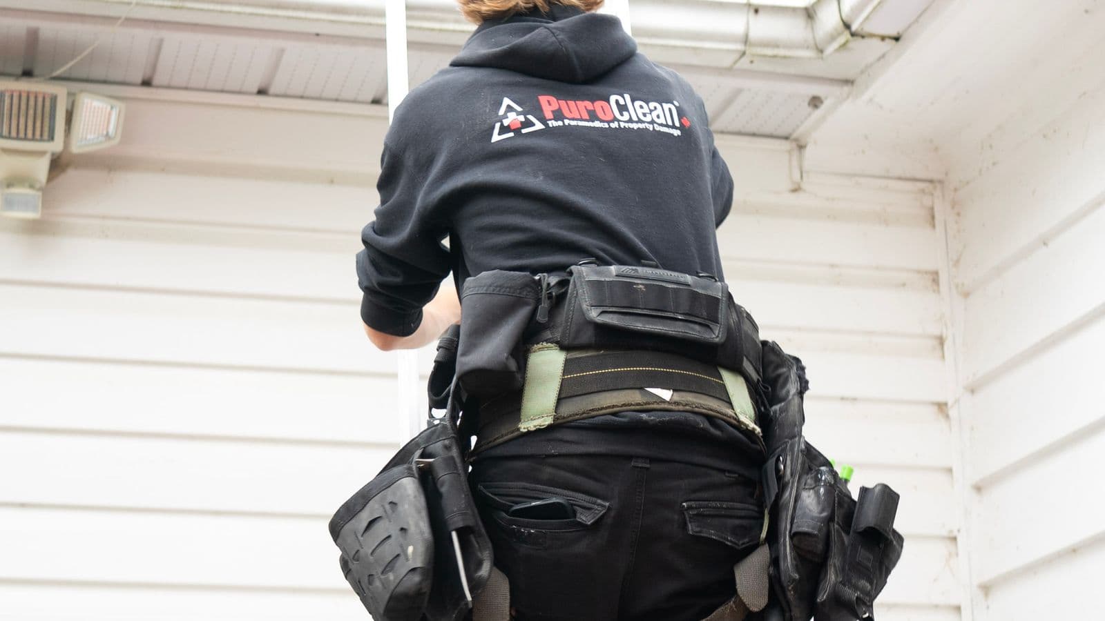 Artisan du nettoyage extérieur montant à l'échelle pour inspecter une toiture