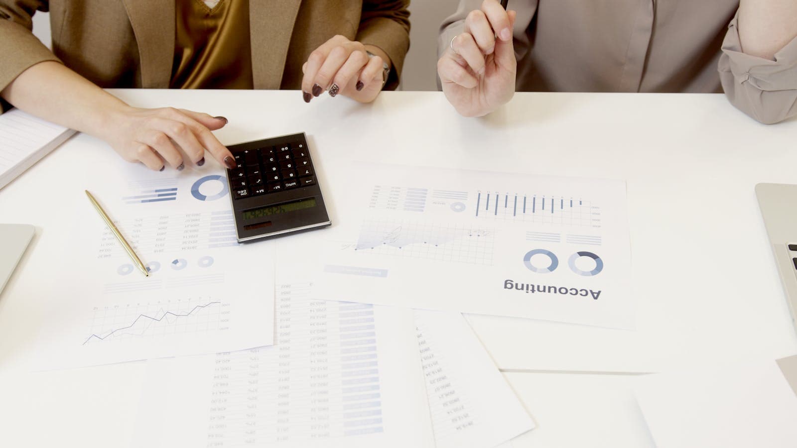 Deux personnes analysant des documents financiers et une calculatrice pour fixer une marge